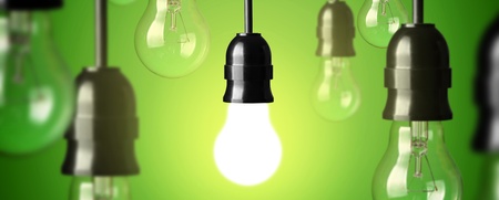 Flera hängande glödlampor mot grön bakgrund, en lampa lyser medan resten är släckta.