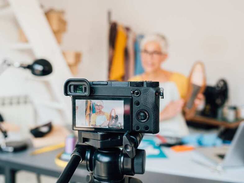 Fotografering med uppställd kamera av kvinna vid skrivbord.