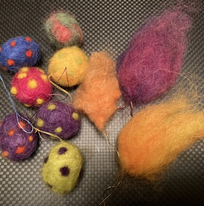 Färgglada ullbollar och former i olika mönster och färger på en mörk bakgrund.