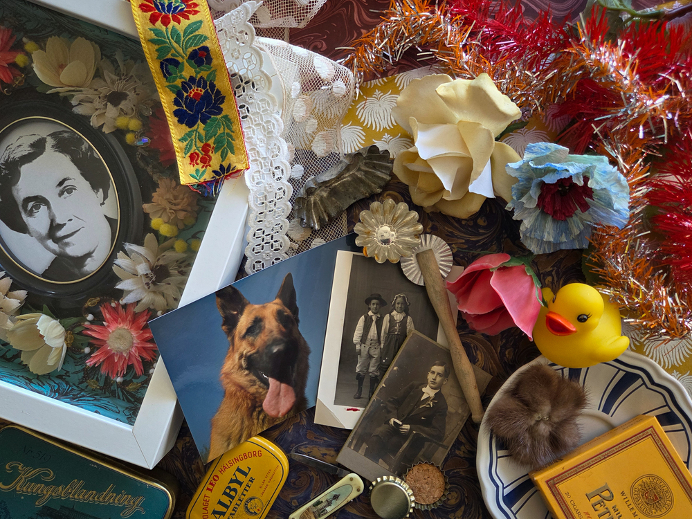 Ett collage med gamla foton, konstgjorda blommor, en gummianka, tennburk och färgglada band.