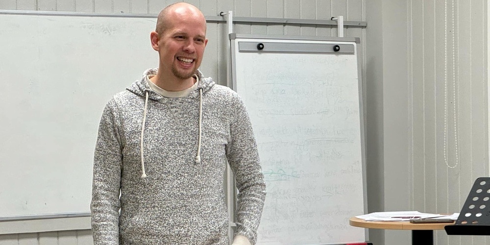 En person står i ett klassrum framför en whiteboard och ett blädderblock.