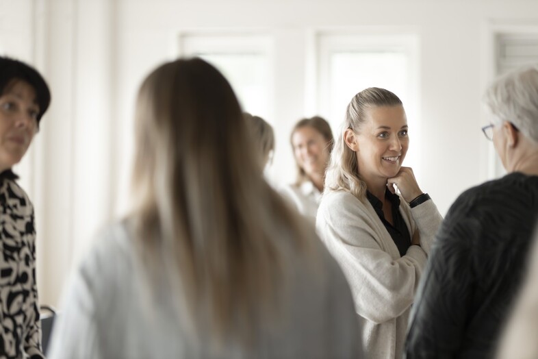 Människor står i ett ljust och pratar med varandra i grupper.