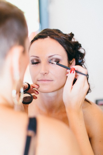 En kvinna får ögonskugga applicerad av en makeupartist med en borste.