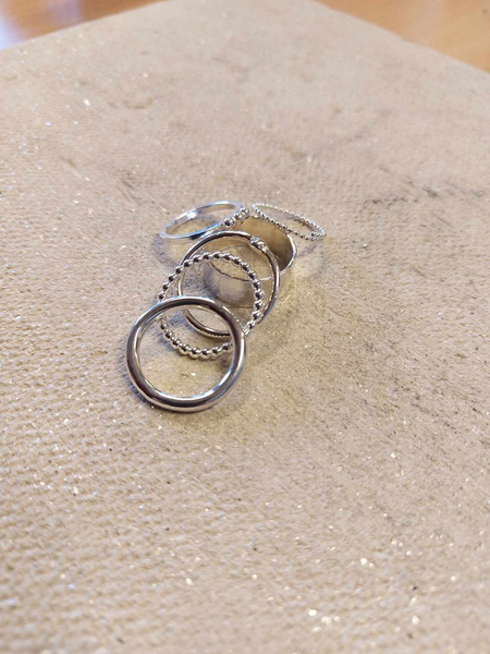 Fem silverringar ligger på en beige, glittrig tygyta.