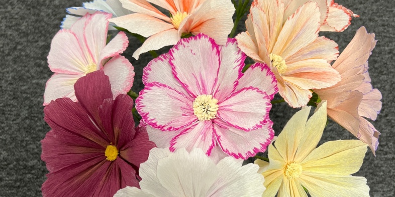 En bukett med färgglada blommor i olika nyanser på en grå yta.