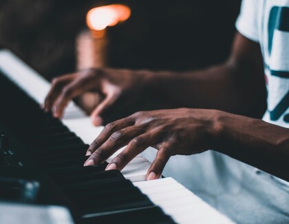 Närbild av händer som spelar på ett piano, med fokus på fingrarnas rörelse över tangenterna.