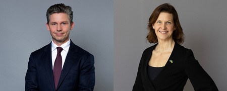 En man i kostym och en kvinna i svart kavaj står mot grå bakgrund, båda ler mot kameran.