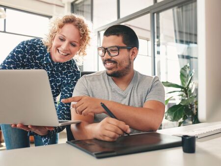 Två personer diskuterar framför en laptop.