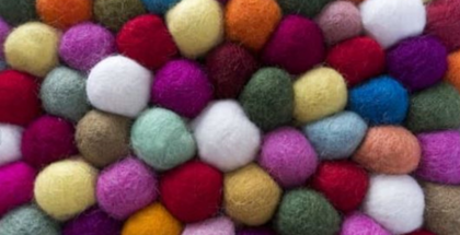 Flera färgglada ullbollar ligger tätt intill varandra i ett mönster.