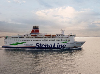En Stena Line-färja seglar på ett lugnt hav under en molnig himmel vid solnedgång.