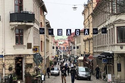 Gata i stadsdelen Haga med gamla trähus, butiker, caféer och människor som promenerar.