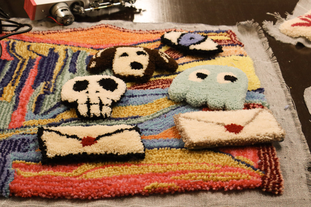 Färgglad matta med tuftade figurer som hund, dödskalle, spöke, öga och kuvert med hjärta.