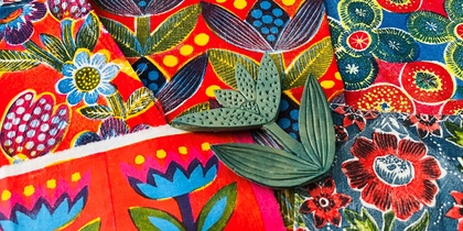 Färgglada tyger med blommönster och två gröna bladformade stämplar ovanpå.