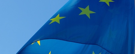 Europeiska unionens flagga med gula stjärnor på blå bakgrund vajar mot en klarblå himmel.