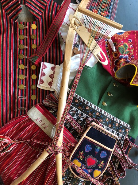 Färgglada traditionella textilier, vävredskap och broderade kläder i rött, grönt och mönstrat tyg.