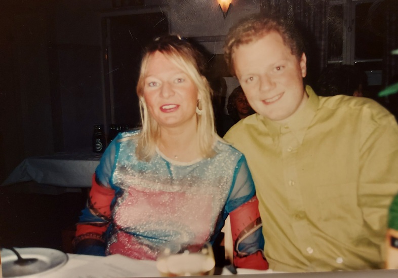 Två personer sitter bredvid varandra vid ett dukat bord på en restaurang, båda ler mot kameran.