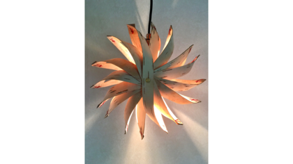 En dekorativ lampa med blomliknande form, tillverkad av böjda blad och upplyst inifrån.