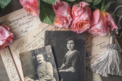 Gamla svartvita fotografier av en man och en kvinna, omgivna av rosor och handskrivna brev.