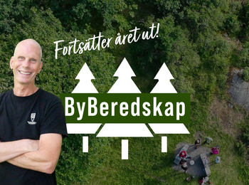 Man ler framför en skogsbakgrund med texten 'Fortsätter året ut! ByBeredskap' och en illustration av tre granar.