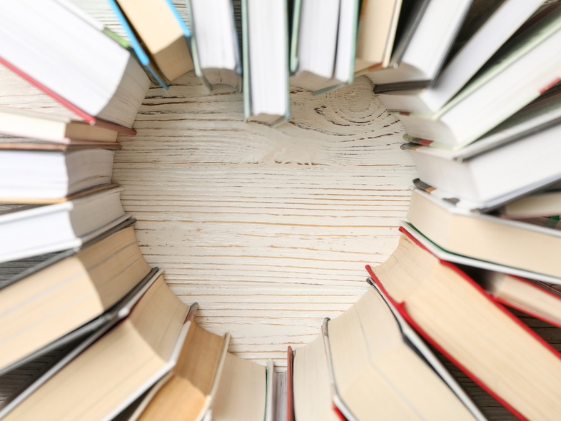 Böcker placerade i en cirkel med ett hjärtformat tomrum i mitten på ett ljust träbord.