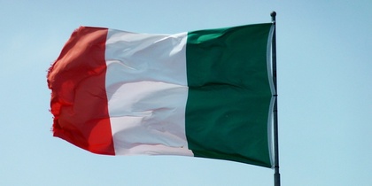 Den italienska flaggan vajar mot en klarblå himmel ovanpå en flaggstång.