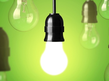 Flera hängande glödlampor mot grön bakgrund, en lampa lyser medan resten är släckta.