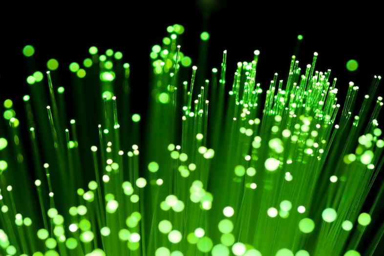 Närbild av gröna fiberoptiska kablar med ljuspunkter mot svart bakgrund.