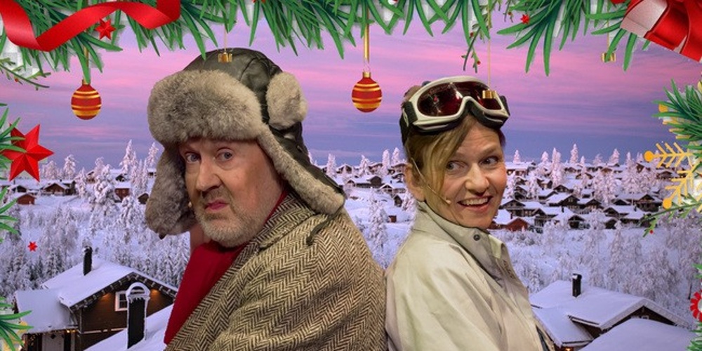 Två personer i vinterkläder står rygg mot rygg framför ett snötäckt bylandskap, inramade av juldekorationer.