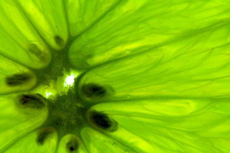 Närbild av en grön citrusfrukt, troligen lime, med synliga kärnor och saftiga segment.