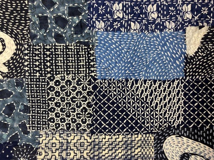 Närbild av ett broderi, boro, med olika blå och vita mönstrade tygbitar.