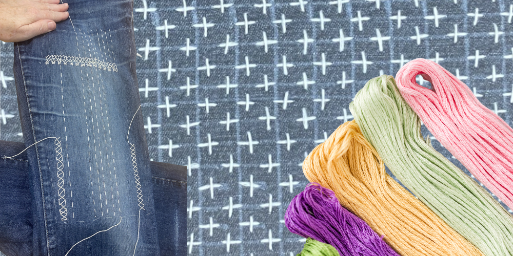 Hand lagar ett par jeans med sashiko-broderi, färgglada broderigarn syns bredvid.