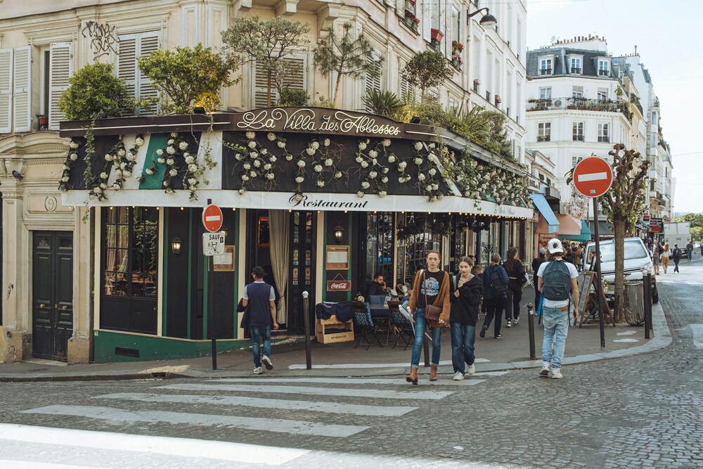 Gatubild av ett parisiskt café med människor som promenerar förbi på trottoaren.