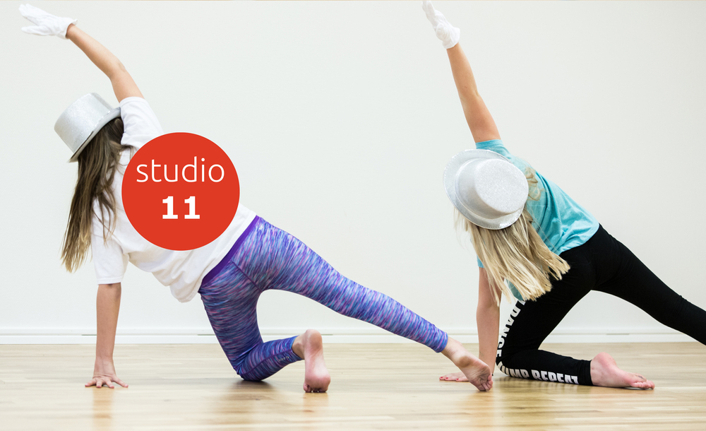 Två personer dansar i studio, bär hattar och handskar, sträcker armarna uppåt mot väggen.