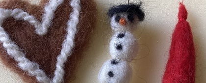 Tre tovade ullfigurer: ett hjärta, en snögubbe och en tomte med lång skägg på ljus bakgrund.