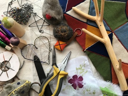 Hantverksmaterial som tänger, tråd, filt, garn och tygbitar på ett bord.