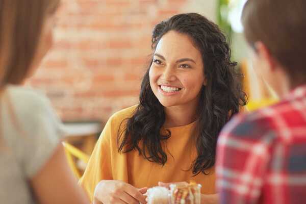 Tre personer sitter vid ett bord och dricker kaffe. Två av personerna har ryggen mot kameran.