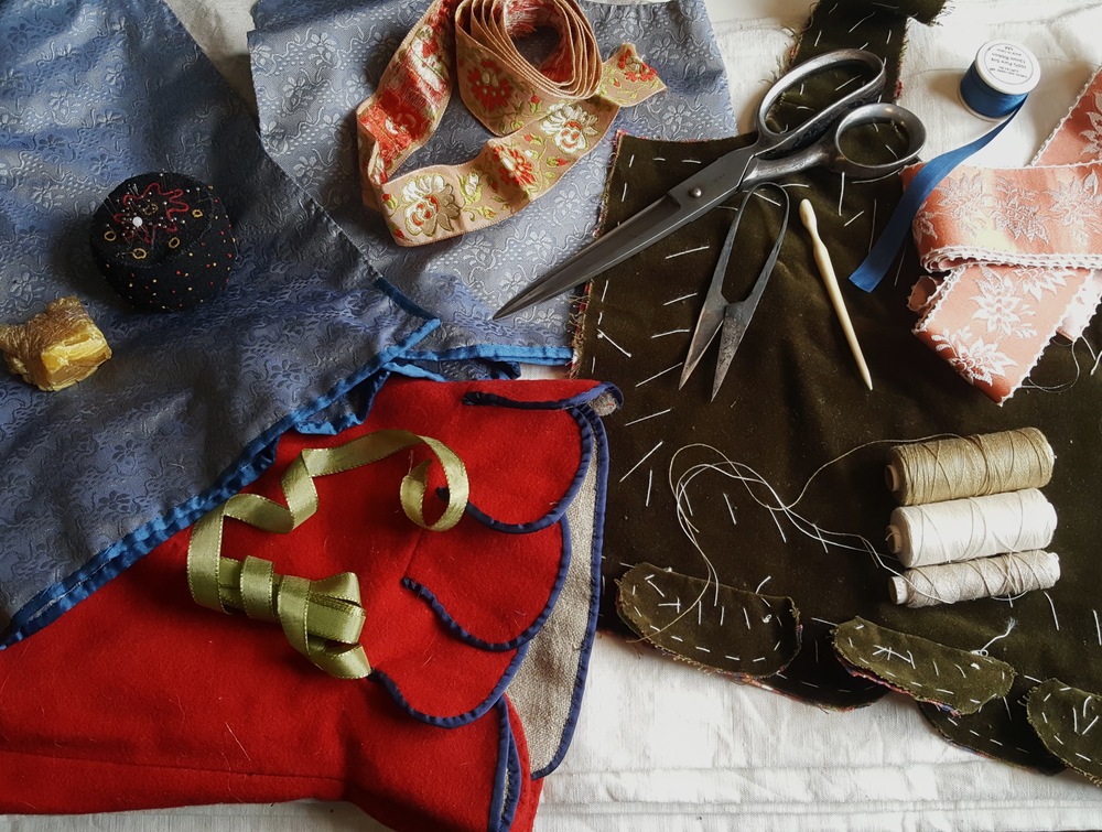 Ett bord med sybehör, tygbitar, saxar, trådrullar, band och nåldyna.
