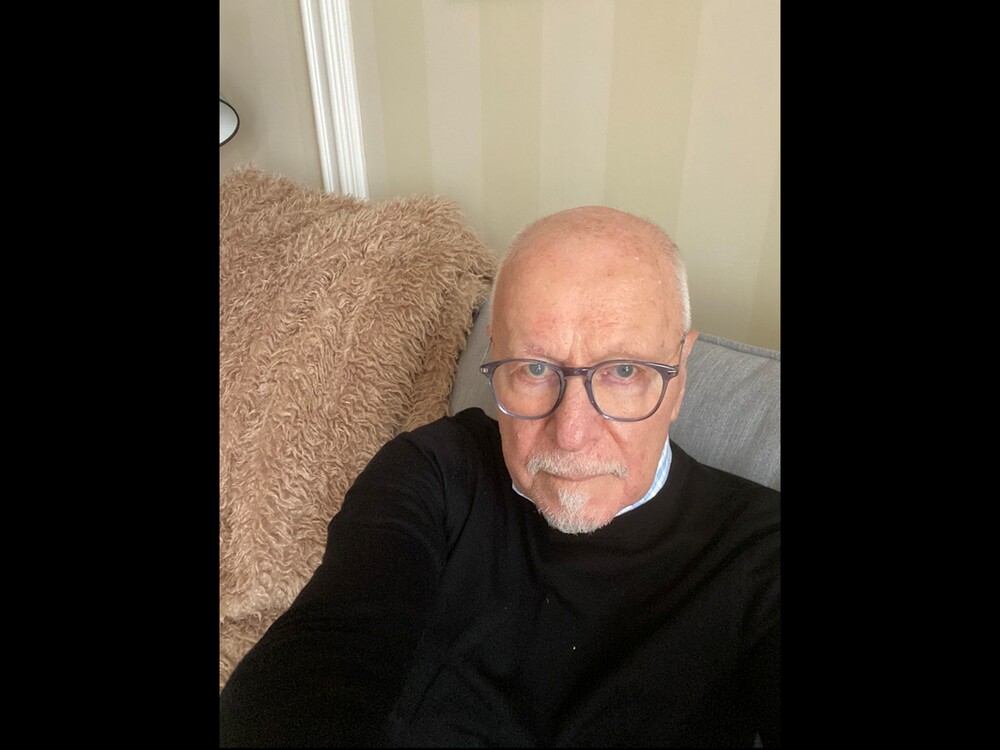 Person i svart tröja sitter i soffa med beige, lurvig kudde bakom sig. Ansiktet är suddat.