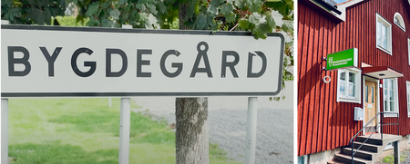 Skylt med texten 'Bygdegård' och en röd träbyggnad med vita fönster och grön skylt.