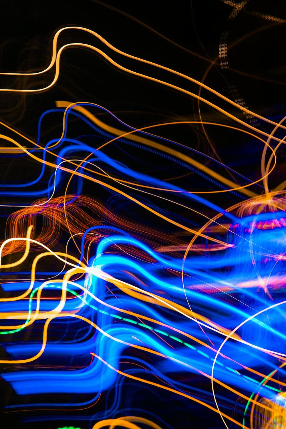 Abstrakt bild med slingrande blå och orange ljuslinjer mot svart bakgrund.