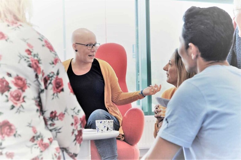 En grupp personer sitter i fåtöljer och diskuterar.