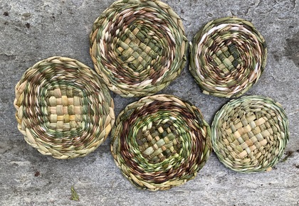 Fem små, runda korgar av flätat naturmaterial ligger på en grå stenyta.