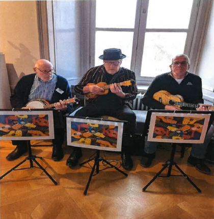 Tre äldre män spelar ukulele och banjo framför notställ i ett ljust rum med trägolv.
