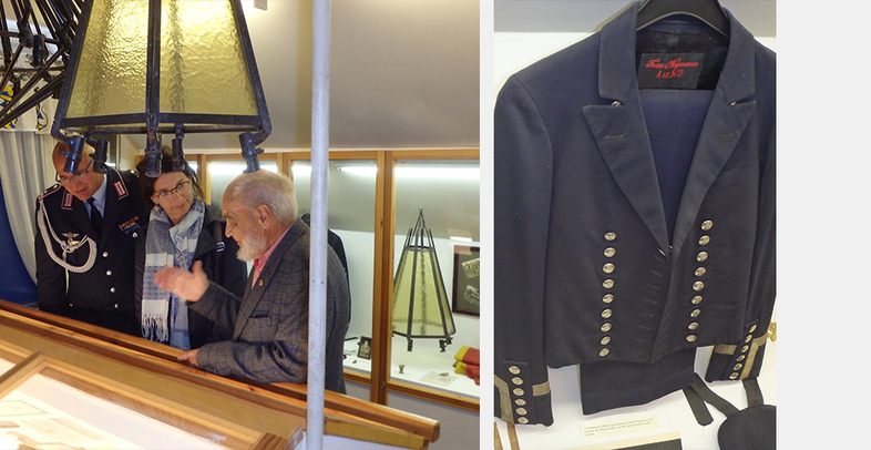 Personer tittar på utställningsföremål i ett museum, inklusive en uniform med många knappar.