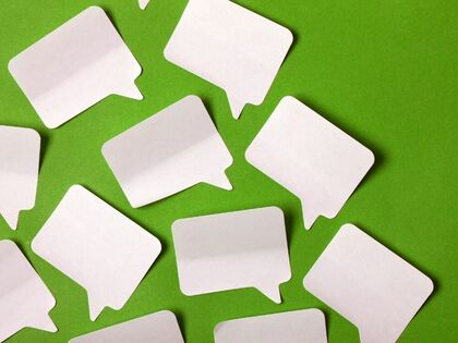 Flera tomma pratbubblor av papper ligger utspridda på en grön bakgrund.