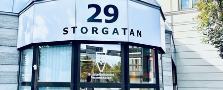 Ingång till byggnad med adressen 29 Storgatan, glasfönster och cykel utanför.