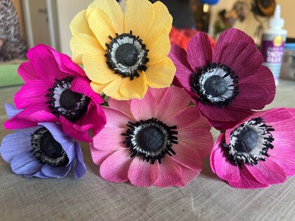 Färgglada blommor av crepepapper i olika färger ligger på ett bord.