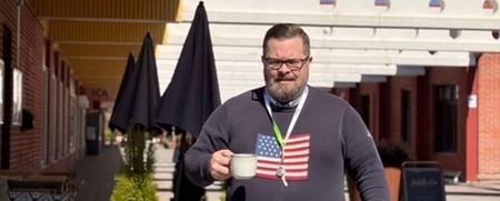 man som går utomhus med kaffekopp i handen och nycklar runt halsen