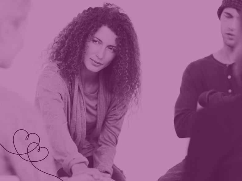 En grupp människor sitter tillsammans och samtalar, en kvinna i fokus sträcker ut handen.