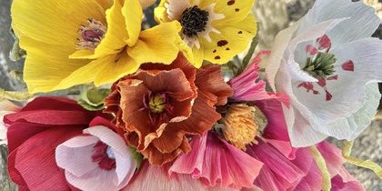 En bukett färgglada pappersblommor i olika former och färger, fotograferad ovanifrån.